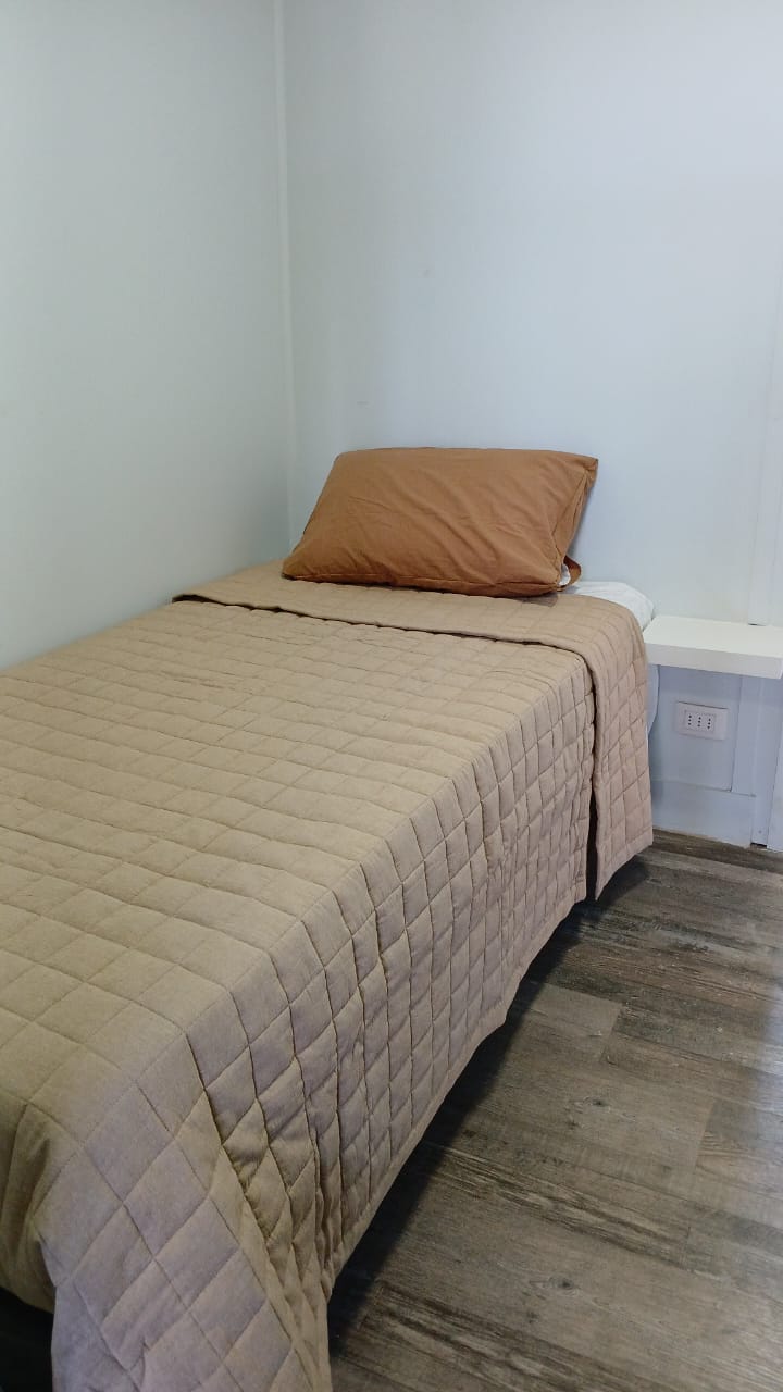Cama con ropa de cama incluida y velador con enchufes